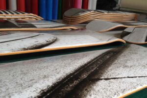 Gestapelte Skateboard-Decks mit fertig zugeschnittenen Digitaldrucken auf Arbeitstisch