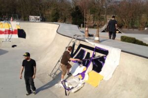 Vans Logo wird mit Folienschablone in Bowl lackiert, im Hintergrund zwei­farbiges Red Bull Logo noch mit Schablone