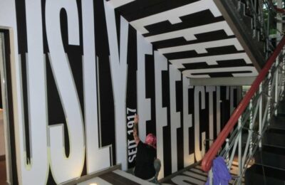 Projektleiterin klebt große Buchstaben ab, um sie mit Wandfarbe nachzumalen